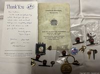 Photo showing all pins, the CNR rules book, and thank you letter laid out on a white surface.