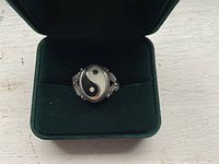 Front view of vintage sterling silver ring with black and white Yin Yang symbol set in oval inlay, placed in dark green velvet ring box.