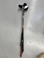 Four golf clubs standing upright showing full shaft and grip on floor