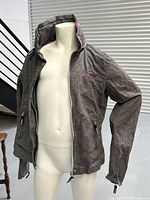 Full view of brown cotton jacket on mannequin showing geometric pattern and zipper closure.