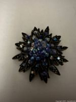 Close-up view of the antique brass star brooch showing central cluster of blue rhinestones and aged metal patina.