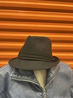Black MILANI bucket hat displayed on a mannequin wearing a zip-up jacket, showing the shape and detailing of the hat from the front and slightly side angle.