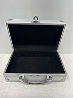 Open portable mini aluminum box showing black felt interior lining and latch mechanism.