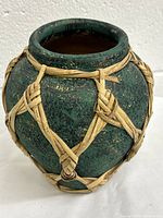 Front view of green glazed clay pot wrapped in intricate rattan pattern showing body and opening.