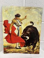 Matador holding red cape facing bull in vintage poster print