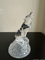 Front angled view of clear lead crystal howling wolf statuette sitting on textured base, highlighting detail and clarity.