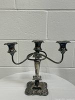 Full view of the silver plated 3-branch candelabra showing ornate detailed base and curved arms for candles.
