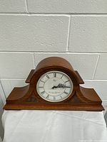 Front view of the wooden Westminster Whittington mantel clock showing curved top and side decorative woodwork.