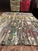 Top-down view of multiple large silk fabric pieces with detailed patterns in gold, silver, and red colors.