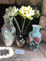 Front view of three vases placed on hearth with decorative flowers in black vase