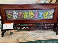 Full view of rectangular framed dragon relief panel on carved wooden stand.