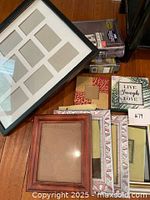 Various assorted picture frames and photo albums neatly arranged on the floor including multi-opening and single frames in diverse styles and colors.