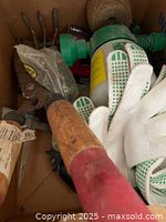 Close up view of handheld cultivator, pruning shears, garden gloves, and garden twine inside a box.