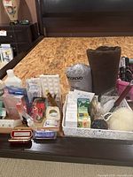 Health and beauty assortment on dark wood surface with bath mats, bar soaps, beauty masks and other boxed personal care items