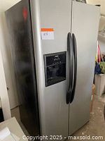 Exterior front view showing stainless steel doors, black side panels, integrated handles, and dispenser location.