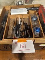 Photo of adjustable wooden drawer tray containing various knives, kitchen shears, and coiled blue utensil holders.