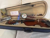 Overview of violin, bow, harmonica, spin drum and string packs inside open case