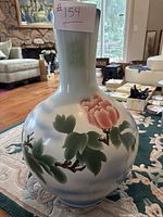 Full view of large painted ceramic vase with floral decoration and embossed Asian characters on neck.