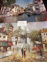 View of both prints showing canal scene above and street scene below on table, note with lot number visible.