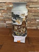 Front side view of the porcelain vase showing two tigers in a nature scene with trees and a waterfall.