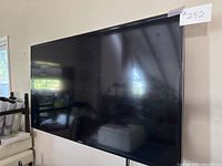 Samsung 60-inch television mounted on wall, showing screen and part of room reflection.