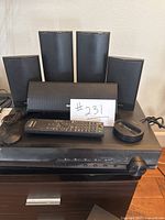 Front view of the Sony home theater system components including AV receiver, five speakers, remote, and accessory on a stand.