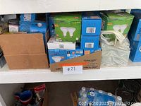 Shelf with boxes of LED lightbulbs in blue and green packaging along with a cardboard box and plastic bag.