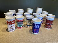 Photo showing 26 vintage collectible plastic cups from Branson, Missouri with multiple artist and Coca-Cola advertisements