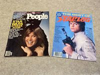 Both magazines laid side by side on a surface. People Weekly shows Carrie Fisher smiling and text about the Star Wars sequel. The Best of Starlog has Luke Skywalker holding a blaster on blue background.