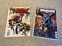 Two DC Comics #1 comic books together on a carpet, Day of Vengeance on the left and Deathstroke Inc on the right, both bagged and boarded.