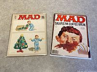Two MAD magazines side by side on a fabric surface, January 1975 and April 1981 issues visible