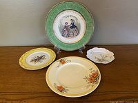 Four decorative plates arranged on a wooden surface showcasing different designs and sizes.