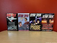 Four Star Trek hardcover novels lined up side by side showing front covers with dustcovers.