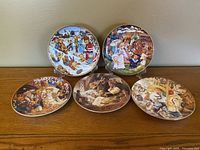 Five Franklin Mint porcelain collector plates featuring teddy bear illustrations, arranged on a wooden surface.