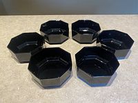Top-down angled view showing all six black hexagonal glass bowls arranged on a table.