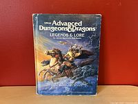 Front cover of the Advanced Dungeons & Dragons Legends & Lore hardcover book showing the title, author names, and fantasy battle artwork.