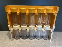 Stacking spice rack with orange and natural wood frame, holding 10 clear glass spice jars with orange lids on top and cream lids on bottom.
