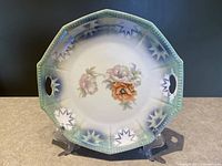 Front view of octagonal porcelain serving plate with flower motif and decorative border, showing cutout handles.