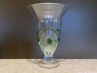 Clear glass art vase with green swirl pattern and ribbed stem on flat base photographed front side overall