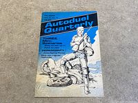Front cover of Autoduel Quarterly magazine Vol. 2, No. 3, featuring blue, black and white artwork showing a figure in armor holding a rifle over a fallen vehicle.