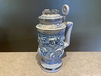 Full front view of the ceramic racing car stein showing detailed relief design, handle, and base.