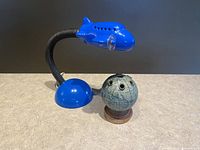 Blue airplane-themed lamp with flexible neck, LED light, sitting next to a vintage map globe pencil holder with pencil slots.