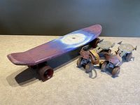 Plastic skateboard with psychedelic tie-dye swirl design and purple wheels, alongside vintage metal roller skates.