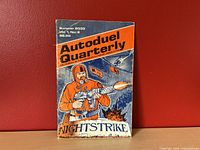 Front cover of Autoduel Quarterly featuring a helmeted figure firing a weapon with helicopters in the background, showing visible wear and stains.
