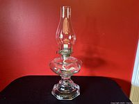 Full view of assembled glass kerosene oil lamp showing clear glass body and chimney with metal wick holder.