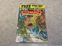 Photo showing full front cover of Combo Magazine #20 in original plastic wrap, featuring colorful insect-like creature and text about Jim Lee, Terry Moore, Star Trek card game, and other comic-related topics.