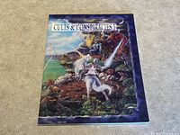 Front cover of Cults & Conspiracies 1 softcover RPG book showing fantasy-themed illustration of characters in an action scene.