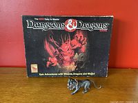 Full view of the game box with red dragon art and Cerberus figurine in front