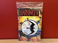Front cover of Harbinger - Children of the Eighth Day graphic novel sealed in plastic, showing title and stylized bird logo over comic art.