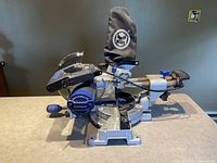 Side view of Kobalt miter saw showing blue motor casing, handle, and dust bag.